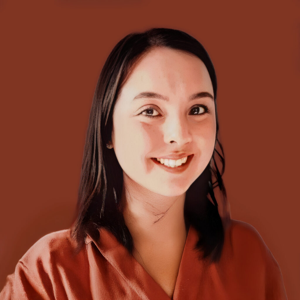 Dr. Alexa Vinh, optometrist wearing a terracota coat, against a warm brown background.